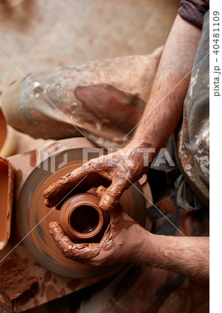 Close-up hands of a male potter in apron making a vase from clay, selective focus 40481109