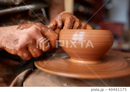 Close-up hands of a male potter in apron making a vase from clay, selective focus 40481175