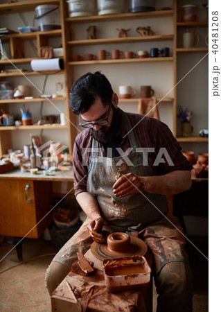 Portrait of a male potter in apron molds bowl from clay, selective focus, close-up 40481208