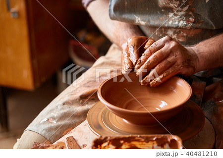 Close-up hands of a male potter in apron making a vase from clay, selective focus 40481210