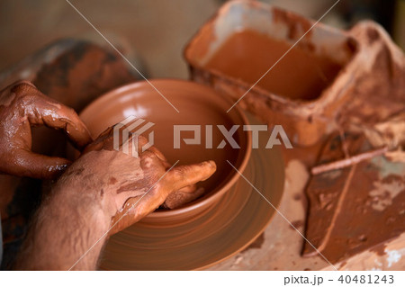 Close-up hands of a male potter in apron making a vase from clay, selective focus 40481243
