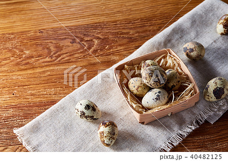 Quail eggs in the container over rustic wooden table, close-up, high angle view, selective focus. 40482125
