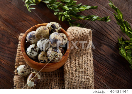 Bowl with eggs quail, eggs on a homespun napkin, boxwood on wooden background, close-up, selective Bowl with eggs quail, eggs on a homespun napkin, boxwood on wooden background, close-up, selective 40482444