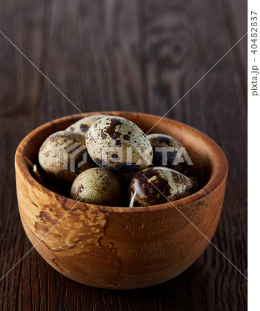 Fresh quail eggs in a wooden bowl on a dark wooden background, top view, close-up Fresh quail eggs in a wooden bowl on a dark wooden background, top view, close-up 40482837