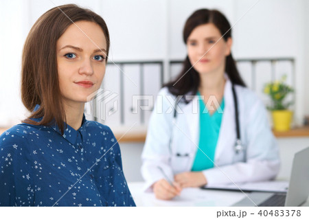 Doctor and patient having a talk while sitting at the desk. Focus on young beautiful woman looking Doctor and patient having a talk while sitting at the desk. Focus on young beautiful woman looking 40483378