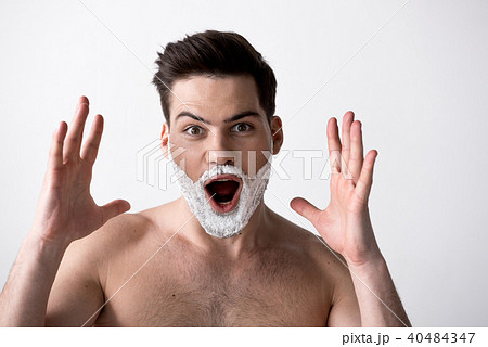 Amazed young man is posing with foam on cheeks Amazed young man is posing with foam on cheeks 40484347