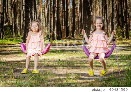 little girls are swinging on swings 40484599