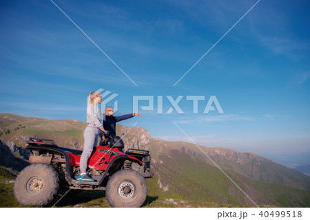 Beautiful couple is watching the sunset from the mountain sitting on quadbike 40499518