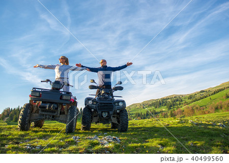 Beautiful couple is watching the sunset from the mountain sitting on atv quadbike 40499560