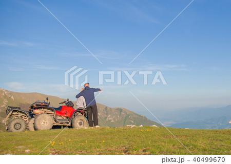 Rear view of young pair near atv. Man is showing something in distance to her girlfriend. Rear view of young pair near atv. Man is showing something in distance to her girlfriend. 40499670