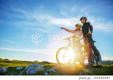 Biker couple with mountain bike pointing in distance at countryside Biker couple with mountain bike pointing in distance at countryside 40499985