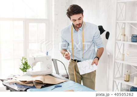 Content professional dressmaker holding his sketches Content professional dressmaker holding his sketches 40505262