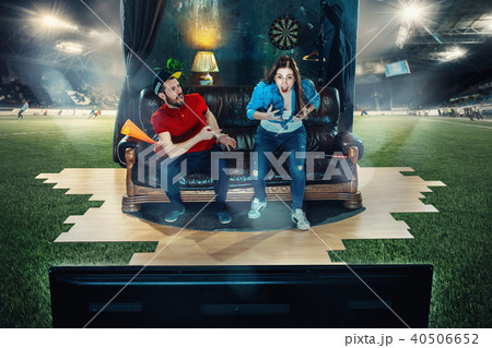 Ardent fans are sitting on the sofa and watching TV in the middle of a football field. Ardent fans are sitting on the sofa and watching TV in the middle of a football field. 40506652