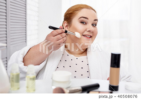 Content fat woman applying make-up Content fat woman applying make-up 40508076