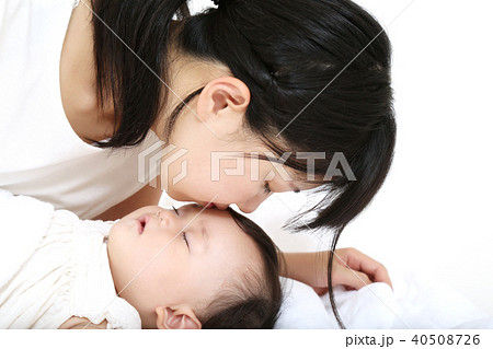 寝ている赤ちゃんのオデコにキスするお母さんの写真素材