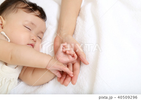 小さな赤ちゃんの手を母の手で包むイメージの写真素材