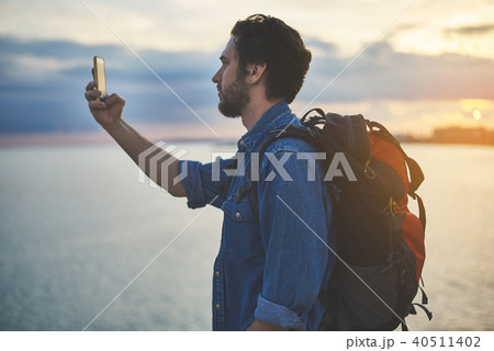 Peaceful male tourist photographing himself near the sea Peaceful male tourist photographing himself near the sea 40511402