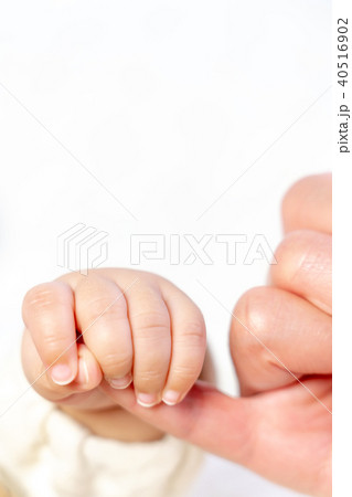 赤ちゃんがバアバの小指を握る クローズアップの写真素材