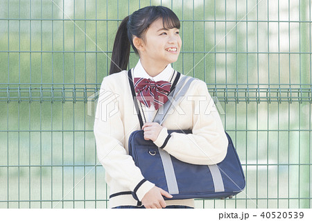フェンスの前を立つ女子校生の写真素材