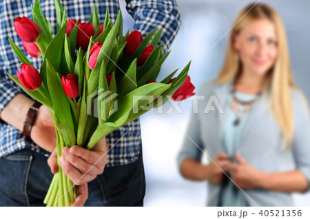 Picture of young man surprising woman with flowers 40521356