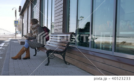 Woman Using Smartphone Relaxes on the Bench in Beautiful Park. Young Woman in making gestures on 40523233
