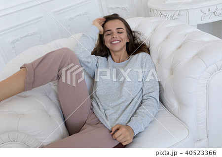 Beautiful smiling woman sitting on a white couch. 40523366