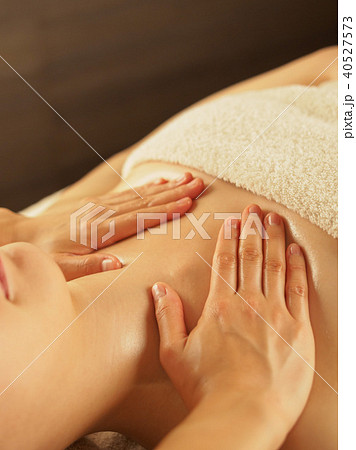 薄暗いエステサロンでデコルテのマッサージを受ける女性の写真素材