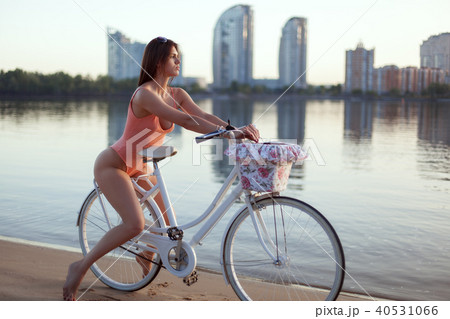 Portrait of a woman in a swimsuit on a bicycle on the river bank. Portrait of a woman in a swimsuit on a bicycle on the river bank. 40531066