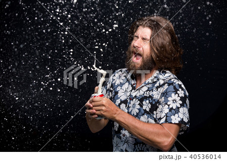 Man opens a bottle of cold beer spraying splashes 40536014