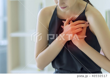 Woman pressing on chest with painful expression Woman pressing on chest with painful expression 40550517