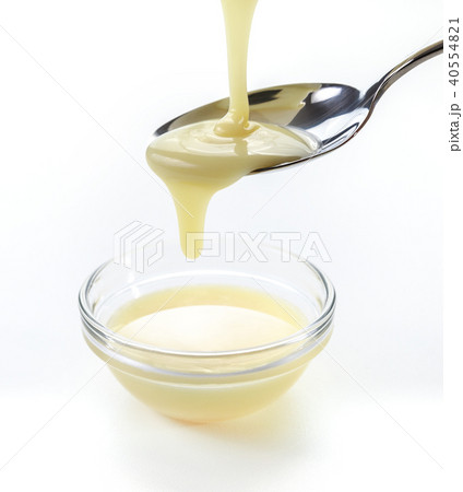 closeup pouring condensed milk with teaspoon closeup pouring condensed milk with teaspoon 40554821