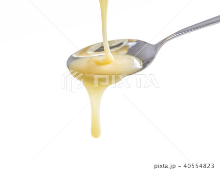 closeup pouring condensed milk with teaspoon 40554823