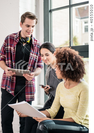 Three young employees using modern devices during break 40555010