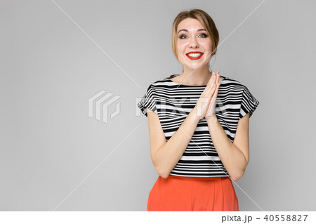 Attractive young blonde girl in striped blouse smiling expressing hope gesture standing on gray Attractive young blonde girl in striped blouse smiling expressing hope gesture standing on gray 40558827