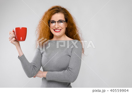 Charming young girl with red hair. A young girl in a gray sweater. Young girl on a gray background 40559904