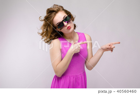 Charming young girl in pink dress on gray background. Cheerful girl in square glasses. The girl Charming young girl in pink dress on gray background. Cheerful girl in square glasses. The girl 40560460