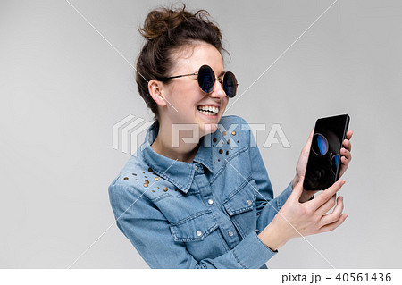 Young brunette girl in round glasses. Hairs are gathered in a bun. Girl with a black phone. The girl Young brunette girl in round glasses. Hairs are gathered in a bun. Girl with a black phone. The girl 40561436