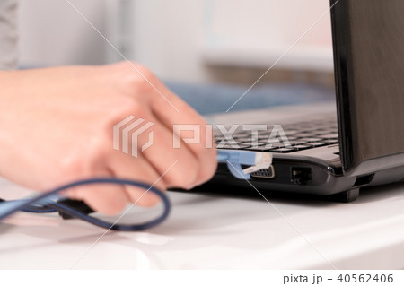 women hand plugging LAN cable to laptop port women hand plugging LAN cable to laptop port 40562406
