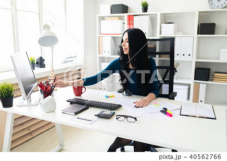 A young girl sits in the office at a table and birches from a pencil vase. A young girl sits in the office at a table and birches from a pencil vase. 40562766