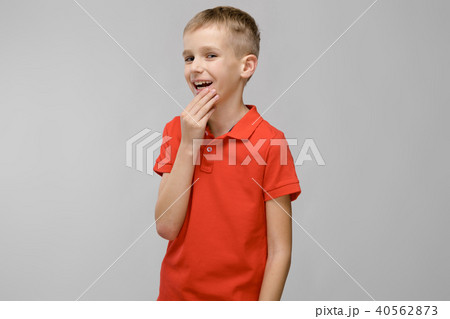 Portrait of little blonde happy smiling caucasian boy in orange t-shirt with hand near his face on Portrait of little blonde happy smiling caucasian boy in orange t-shirt with hand near his face on 40562873