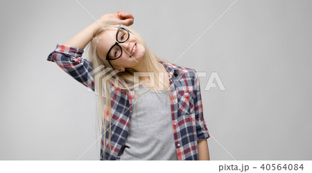 Beautiful teen girl with long hair and wearing glasses. A teenage girl in a plaid shirt and a gray T Beautiful teen girl with long hair and wearing glasses. A teenage girl in a plaid shirt and a gray T 40564084