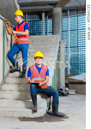 Asian workers on building or construction site walling 40564135