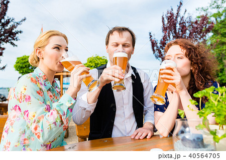 Friends toasting with beer in garden restaurant 40564705