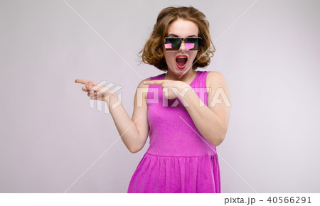Charming young girl in pink dress on gray background. Cheerful girl in square glasses. The girl 40566291