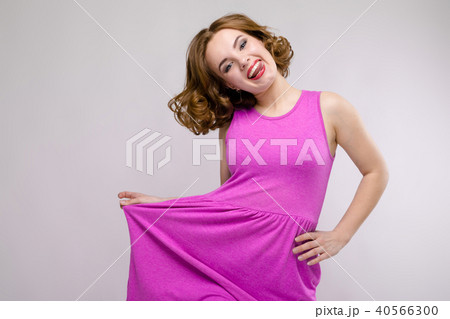 Charming young girl in pink dress on gray background. Young girl pulls her hand out 40566300