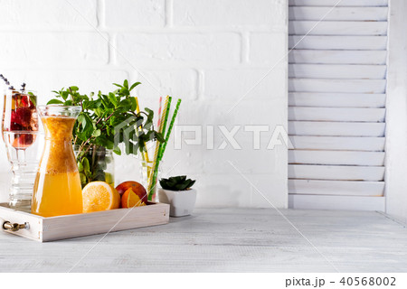 Orange lemonade in the decanter on a wooden tray with ftuits and mint 40568002