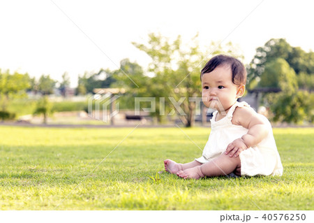 公園の芝生の上に座り一人遊ぶ女の子の赤ちゃん 40576250