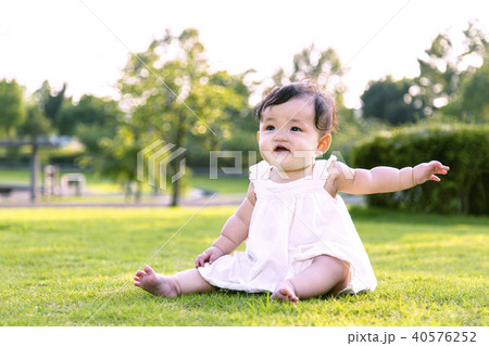 公園の芝生の上に座り一人遊ぶ女の子の赤ちゃん 40576252