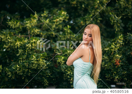 Blonde girl in turquoise color dress posing to the photographer 40580516