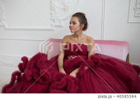 Cheerful young woman in a burgundy ball gown. 40585564